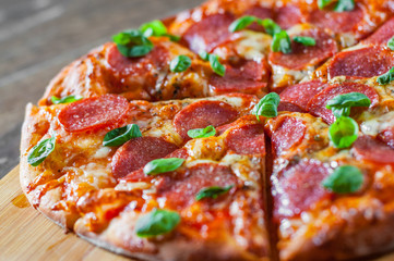 Pepperoni Pizza with Mozzarella cheese, salami, Tomatoes, pepper, Spices and Fresh Basil. Italian pizza on wooden table background