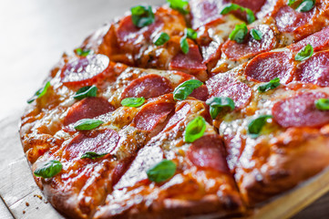 Pepperoni Pizza with Mozzarella cheese, salami, Tomatoes, pepper, Spices and Fresh Basil. Italian pizza on wooden table background