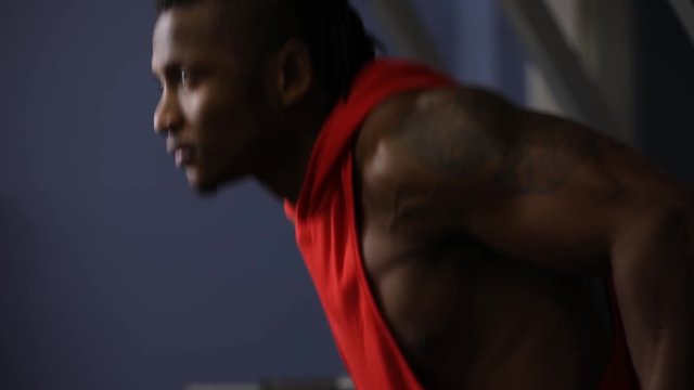 African american man push ups in gym on parallel bars