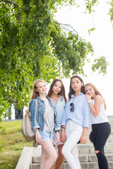 Fototapeta premium Full length portrait of charming young student girls in the Park in summer. Women wear pastel colored clothes, sneakers and shoes. Friendship, weekend of the concept