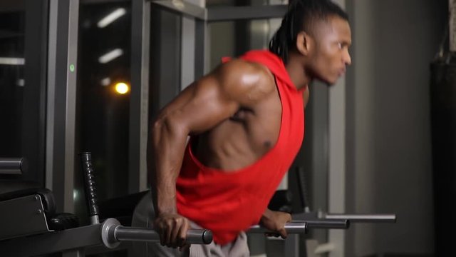 African american man push ups in gym on parallel bars
