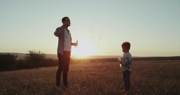 Spending a perfect time together dad and son at nature amazing sunset , making bubbles.