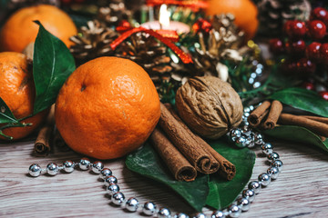 Christmas composition of tangerines, cinnamon sticks, spruce fir branches, walnuts, and brilliant decorations