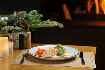 salmon fillet with carrots, basil and red caviar, against the background of the Christmas tree and fireplace