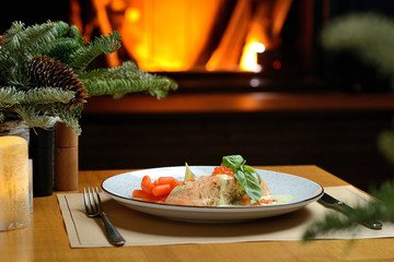 salmon fillet with carrots, basil and red caviar, against the background of the Christmas tree and fireplace