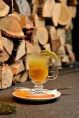 Sea buckthorn tea in a transparent glass on the background of wooden logs, Christmas tea