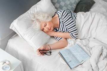 View from above. Grandmother sleep near book and eyeglasses