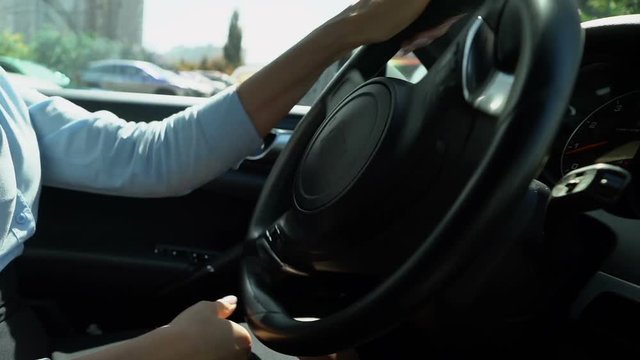 Female driving car back into parking spot, attentive driver closeup reverse gear