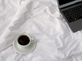View of coffe cup, white bed, notebook. Home working mock up. Copy space.