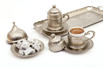 Turkish coffee in traditional silver cup with Turkish delight on isolated white background