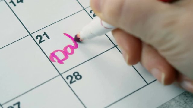 Write with a pink marker on the calendar to date with heart. Close up 4k footage.