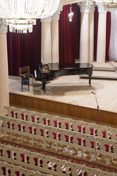 Piano on scene and empty chairs in the concert hall