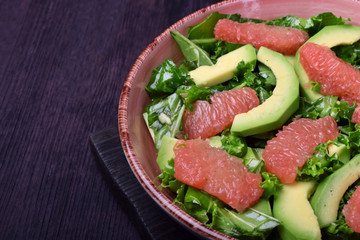 Salad with kale, avocado and grapefruit against the dark background
