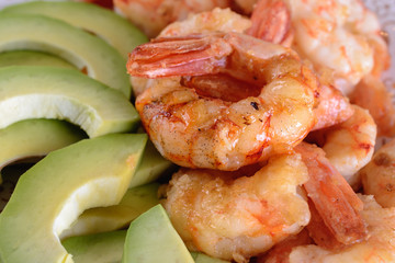 Grilled shrimps next to fresh avocado slices, macro