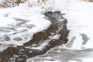 A detailed look at the water runs under the ice, the water from the tap flows into the stream