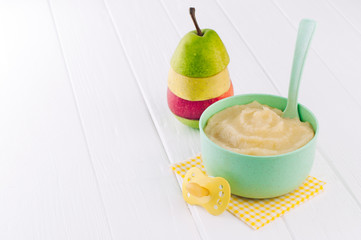 Apple and pear puree in bowl near apple on white background with copy space