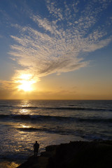 Silhouette of a man standing on a cliff watching the sunset in La Jolla California