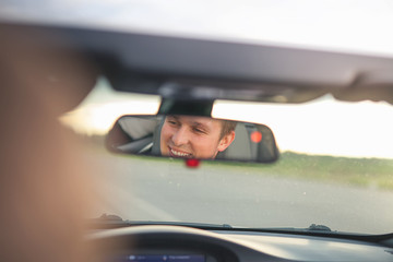 Portrait of man smiling into the car mirror