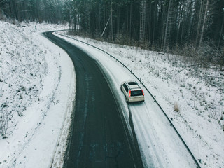 view from above aerial suv car at roadside in snowed highway in forest