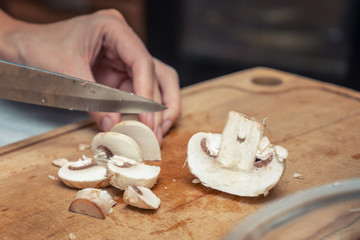 Fototapeta na wymiar Girl cook is cutting mushrooms on a wooden Board