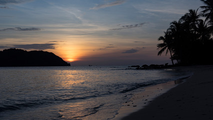 Beautiful charming sunset by the sae on the beach of Phu Quoc island with beautiful view of palms,mountains and orange sky
