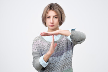 portrait of attractive caucasian woman showing time out sign isolated on white studio shot looking at camera