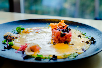 tar-tar from tuna. Tuna in pumpkin sauce with herbs and seafood on a plate