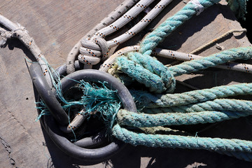 Lots of rope knots leading to moored boats. Iron mooring rings. Concrete pier surface. Nautical...