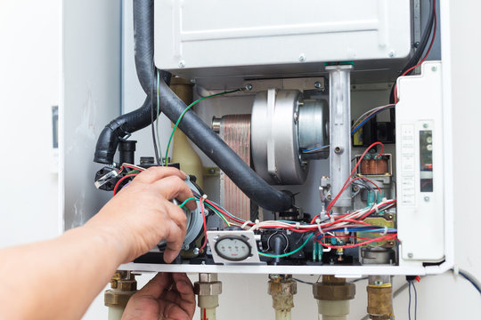 worker set up central gas heating boiler at home