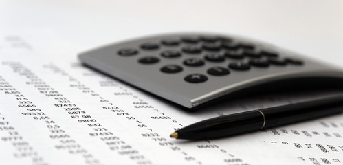 Financial accounting, Image a plurality of numbers on paper and calculator, Numbers on paper, a pen and a calculator.