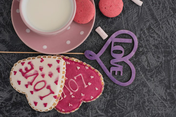 Romantic Valentine's Day breakfast. Heart-shaped cookies and a cup of milk on a gray table. Top view