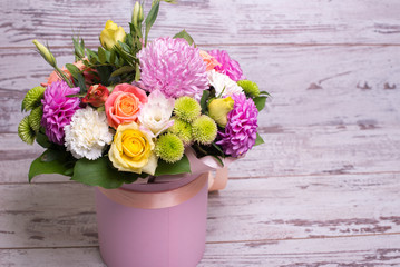 beautiful floral arrangement in the box, pink and yellow rose, pink eustoma, green and pink chrysanthemum, white carnation, dahlia on wooden background, top view, with space for text