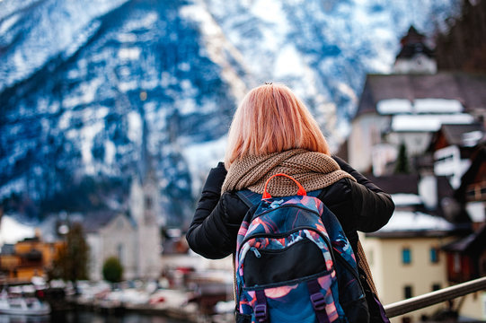A girl with a backpack, a tourist, photographs the view of Hallstatt