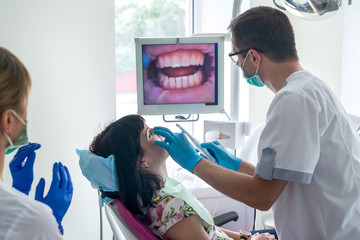 Dentist checking patient's teeth with intraoral camera