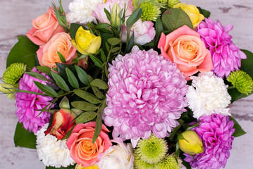 beautiful floral arrangement in the box, pink and yellow rose, pink eustoma, green and pink chrysanthemum, white carnation, dahlia on wooden background, top view, with space for text