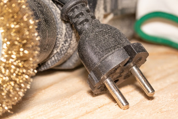 Electric drill with disc for processing wooden surfaces and gloves on a wooden joinery table.