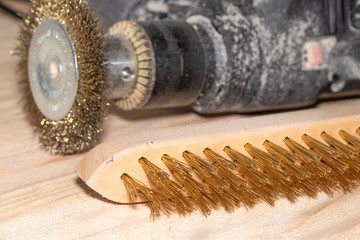 Electric drill with disc for processing wooden surfaces and a metal brush on a wooden joiner table.