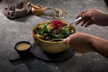 hands mixing salad in a bowl 