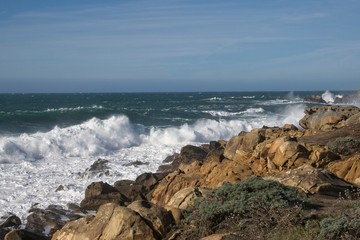 Strong winds and large waves dominate the rocky shoreline.