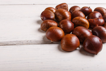 pile of sweet chestnuts on white wooden background