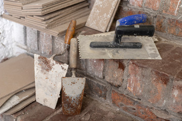 Laying tiles on the stairs in the basement. Prepared tiles and tools in the utility room.