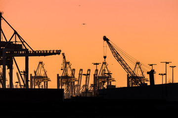 Cranes silhouetted against the evening sky in Hamburg Harbor, Germany, at dusk. The Port of Hamburg (Hamburger Hafen) is a sea port on the river Elbe. It is Germany's largest port.