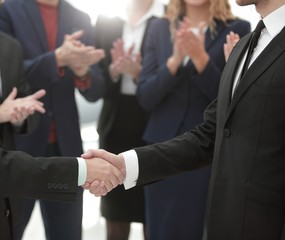 close up. handshake of business partners on the background of applauding business team