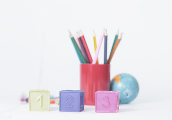 cubes with numbers on blurred school supplies background