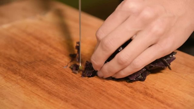 Closeup of the hands of a girl at the home kitchen on a wooden cutting board small cherry tomatoes. Home cooking