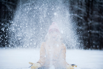 Fototapeta na wymiar Very beautiful bright young girl in a red hat and yellow mittens on the background of a winter park in the snow. Winter holidays concept.