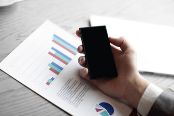 close up.the businessman uses his smartphone to check financial 