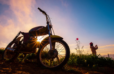 Beautiful sunset and vintage motorcycle with women in background.