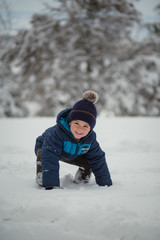Fototapeta na wymiar Adorable, cute, little boy enjoying winter, playing in the snow