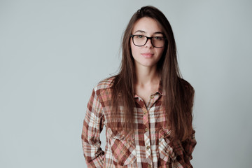 Self confident cute young brunette girl in lumbercheck check shirt and glasses